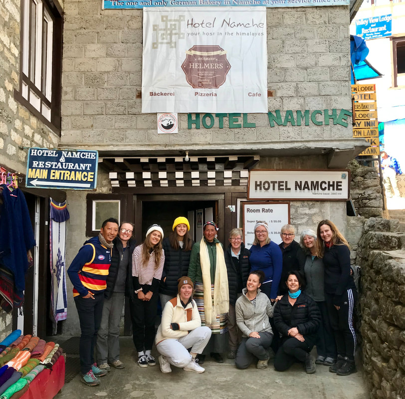 A group of women and one man standing out the front of a hotel in a town in Nepal, part of the Everest Base Camp Trek
